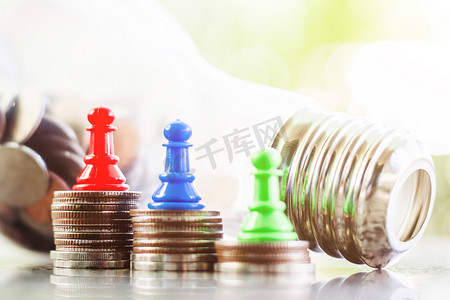 绿色灯泡摄影照片_棋典当在硬币的顶部和电灯泡瓶形状反对模糊的自然绿色背景为投资、商业、财政和省钱概念