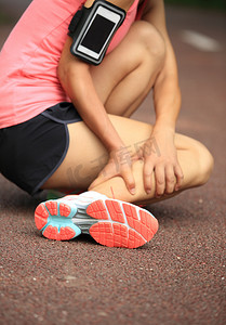 运动鞋摄影照片_女跑步运动员扭到脚踝受伤