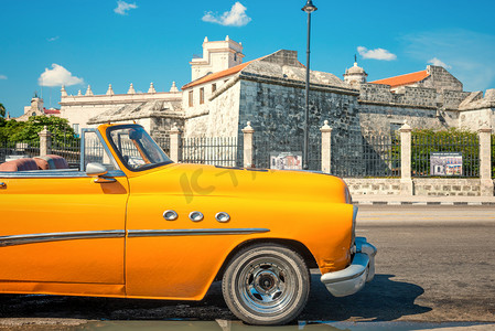 老式汽车停在一座古堡在哈瓦那旁