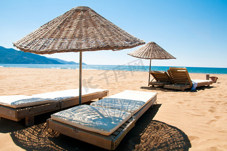 在沙海边的日光浴浴床和藤遮阳伞.