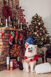 耶摄影照片_女人附近与萨摩耶犬的圣诞树