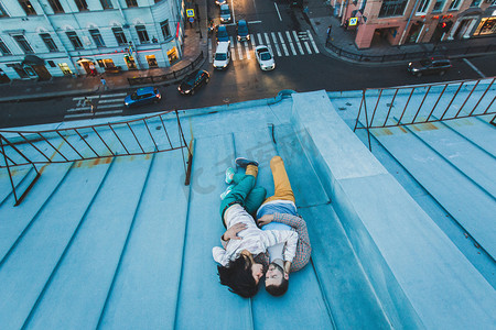 浪漫屋摄影照片_年轻的时髦夫妇躺在屋顶上 