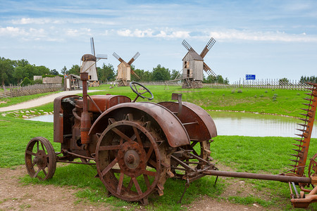 农业风车摄影照片_旧拖拉机和风车。爱沙尼亚