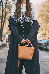 黑色购物摄影照片_关闭了时尚的细节，年轻的商界女人抱着她棕色的优雅包。戴着黑色和金色手表。理想弹簧装配件.