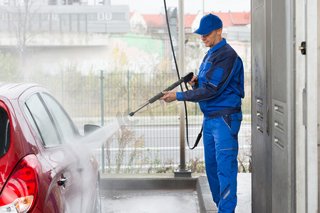 车库摄影照片_用高压水射流洗车的蓝领工人
