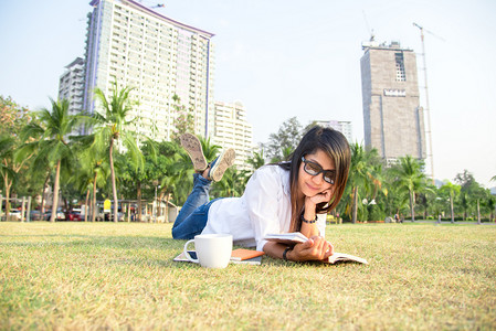 看得见的幸福摄影照片_女孩喜欢看书喝咖啡休息时间与户外公园草地上铺设