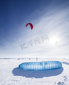 雪摄影照片_kiteboarder 与蓝风筝在雪地上