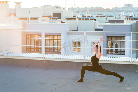 欧美户外运动摄影照片_做瑜伽在屋顶上的年轻女子