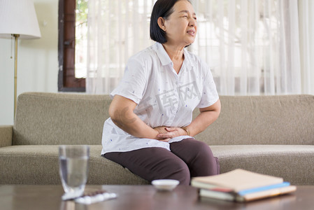 老女性摄影照片_年长亚洲妇女在家中疼痛，老年女性患腹痛