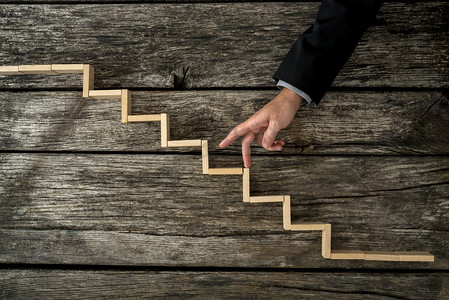 fingers摄影照片_Businessman or student walking his fingers up wooden steps