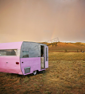 沙漠创意背景摄影照片_可爱的老式露营车拖车在锯齿山脉在一个荒凉的营地在夏季暴雨与彩虹在距离色调与复古复古 instagram 过滤器 