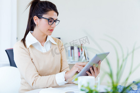坐在办公桌前使用数字平板电脑的年轻女企业家 