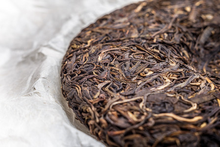 水墨普洱茶摄影照片_老沈中国发酵的普洱茶在纸莎草纸纸张背景微距特写 