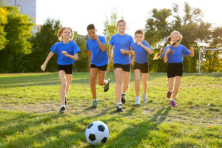 小学体育锻炼摄影照片_可爱的孩子在球场上踢足球
