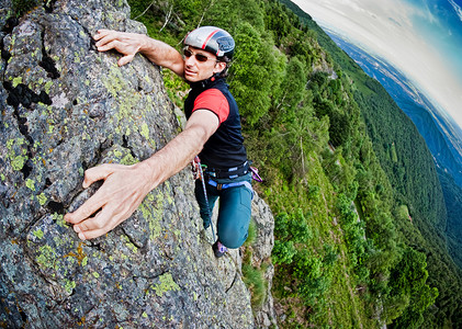 登山运动摄影照片_年轻的白人男子攀爬陡峭壁