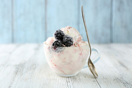 美味的冰淇淋摄影照片_美味的冰淇淋，与新鲜冷冻浆果，颜色木制背景