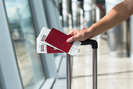 Closeup of man holding passports and boarding pass at airport