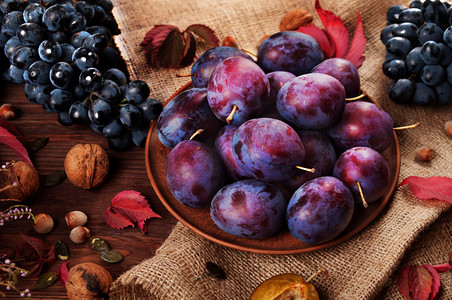 多汁的梨，躺在泥板。接近葡萄、 坚果和红色的树叶。秋季水果静物.