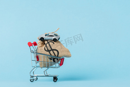 little shopping trolley with dollar bag and toy car on blue, leasing concept
