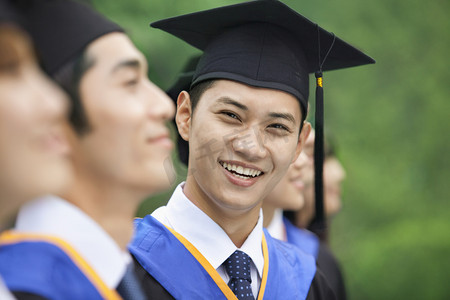 毕业摄影照片_高考在一排的年轻的大学毕业生中微笑的人