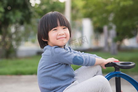 儿童学步车摄影照片_亚洲儿童户外驾驶蓝色玩具车