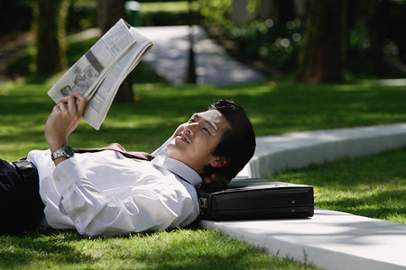 企业祝福摄影照片_一个男人躺了下来，读报纸
