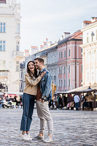 欧美拥抱摄影照片_在城市里，男朋友和女朋友拥抱在一起，望着远方，微笑着