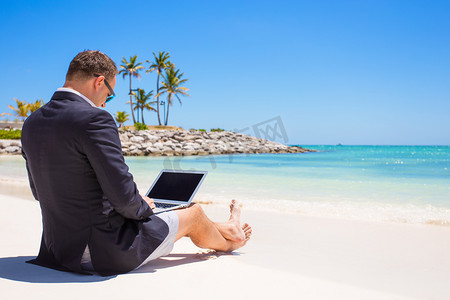 商人在热带海滩上使用便携式计算机