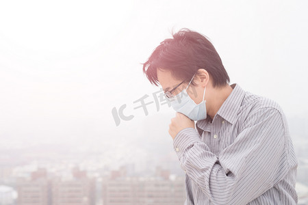 预防三高摄影照片_亚洲人戴着口罩行走在雾霾中的人
