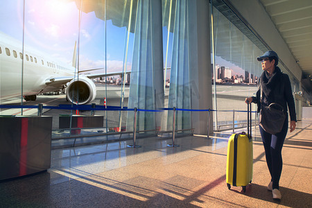 旅行的女人和行李在机场候机楼和飞机飞向外边走