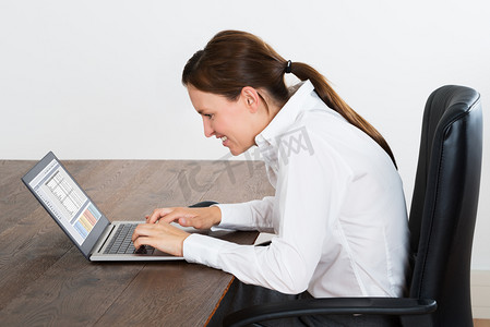 快乐的女商人在笔记本电脑上工作