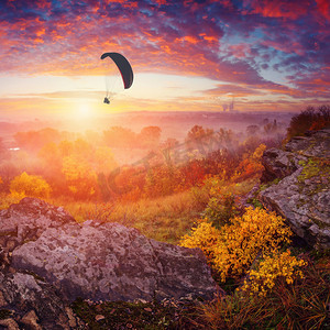 人物海报背景摄影照片_ 迷雾笼罩的山谷上方户外天空滑翔伞