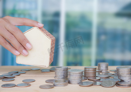 财政资源摄影照片_未来为2021年的概念存钱。带有蓝色背景的木制半圆形房子的硬币。供现金购房用的物品.
