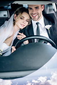 欧美拥抱摄影照片_有吸引力的新娘在新娘面纱拥抱英俊的新郎在汽车 