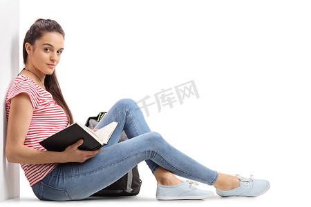 背包猪摄影照片_十几岁女生拿着一本书坐在地板上