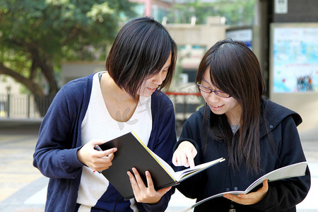 教室书架摄影照片_在研究和讨论在大学的亚洲学生