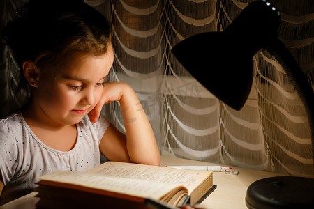 小女孩看书摄影照片_漂亮的小女孩看书坐在桌下灯儿童和教育