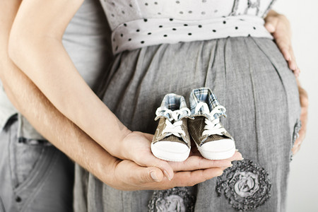 初生婴儿靴在父母手中。关闭.