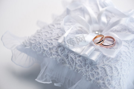 结婚金色摄影照片_在花边枕头上的结婚戒指