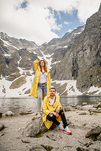在波兰 Morskie Oko 湖附近散步 intatra 山的黄色雨衣年轻夫妇