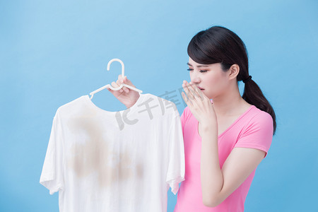 字体麻烦摄影照片_蓝色背景的妇女嗅到肮脏的衬衣