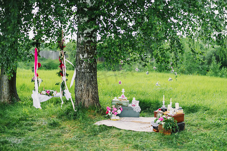 粉色花朵装饰摄影照片_装饰区域为婚礼与秋千, 花, 和装饰在户外树下