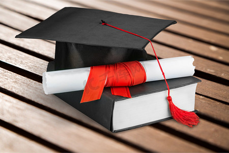 研究生考试摄影照片_木制桌上的毕业帽、书和文凭