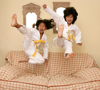 中国家庭日摄影照片_两个小亚洲柔道输入器跳上沙发