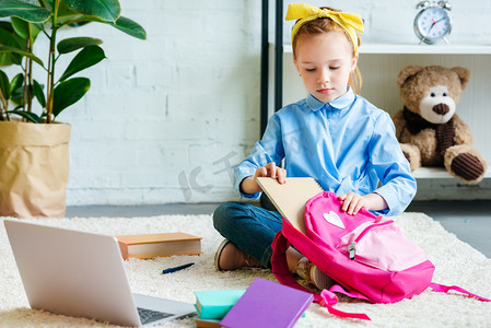 小孩子摄影照片_可爱的小孩子打包书包, 而坐在家里的地毯上