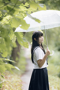 在雨中漫步在自然人行道上的亚洲学校女孩肖像