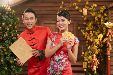 彩色信封摄影照片_爱好亚洲情侣穿着中国传统服饰, 展示彩色信封 