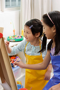 Two girls painting on easel