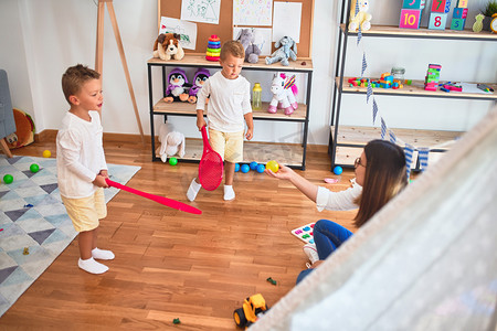 幼稚园里，漂亮的老师和幼儿用球拍在许多玩具周围打网球