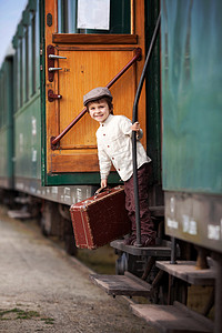 男孩，身穿老式衬衫和帽子，带着手提箱